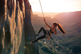 Athletic woman climbing a mountain on a rope
