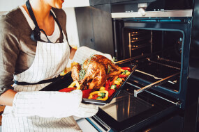 Woman takes a roasted chicken out of the oven