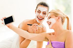 Two girl friends with face masks on taking a selfie