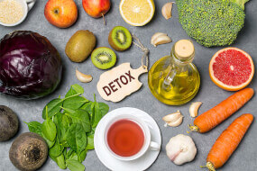 Flatlay of healthy vegetables, fruits and olive oil on a table with detox lable