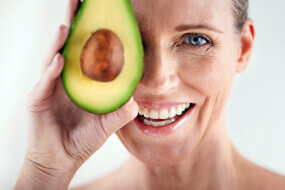 Older woman smiling with half an avocado