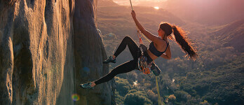 Athletic woman climbing a mountain on a rope Athletic woman climbing a mountain on a rope