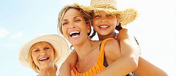 Three generations - daughter, mother and grandmother, smiling at the beach, wearing sun hats Three generations - daughter, mother and grandmother, smiling at the beach, wearing sun hats