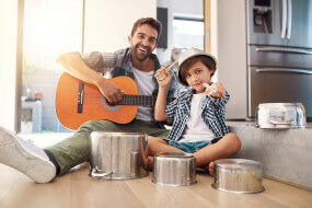Father and his son playing the guitar and pots as drums